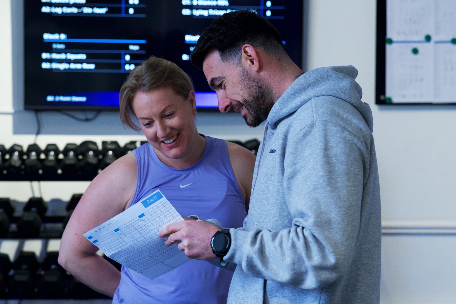 A SixFour Fitness coach going through a member&rsquo;s programme card with her during a one-to-one session